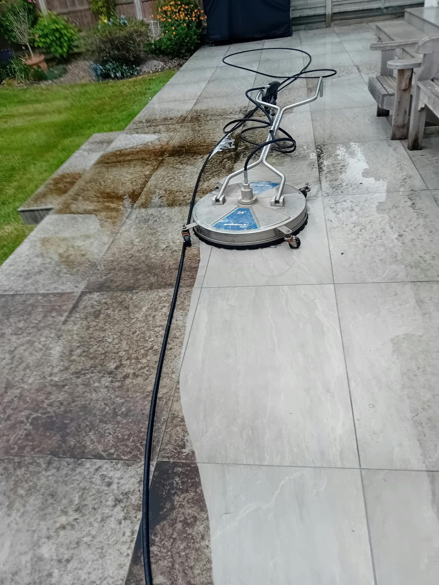Porcelain patio being pressure washed with a rotary surface cleaner, cleaned stone against dirty stone
