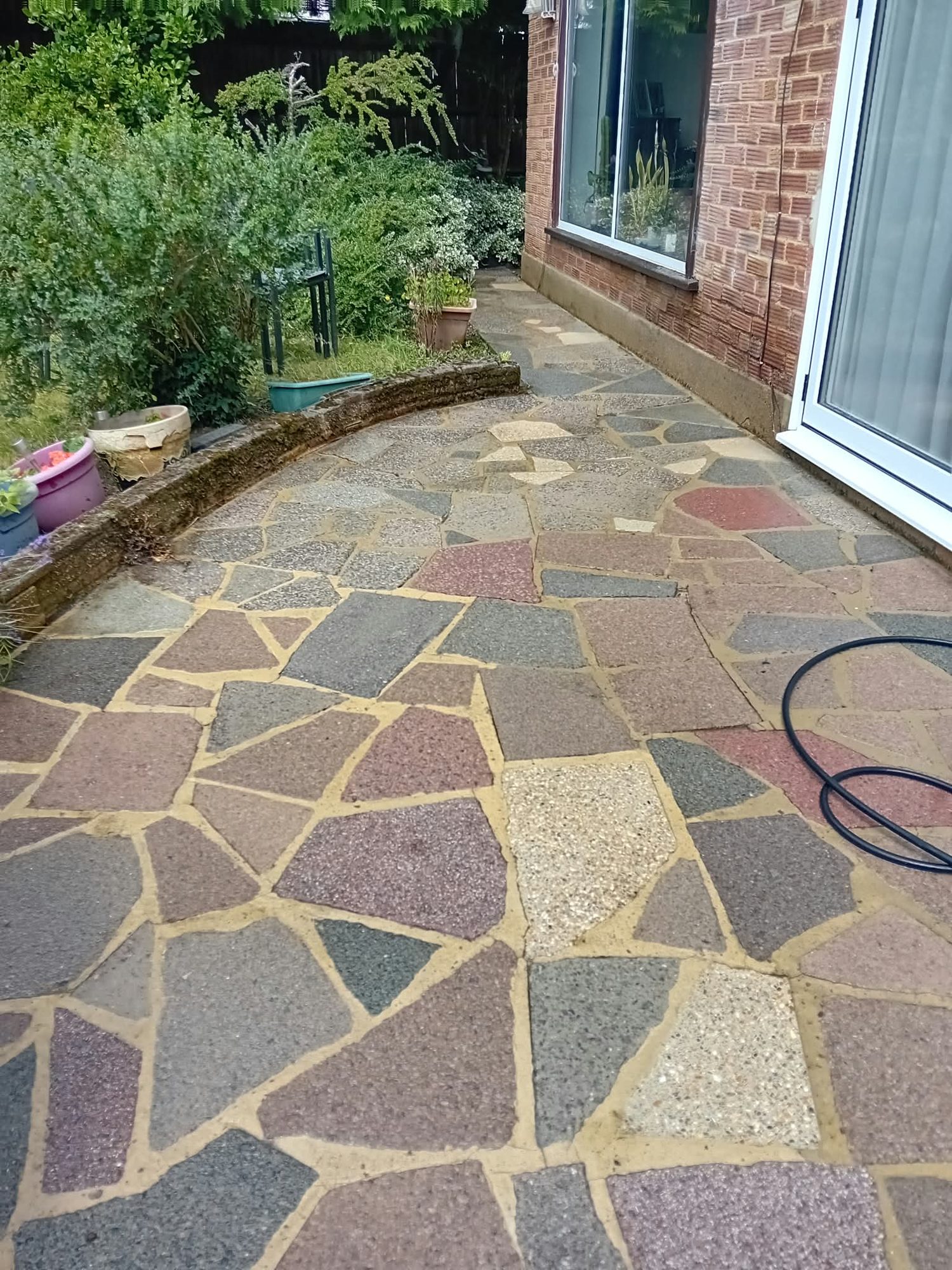Crazy-paving patio path alongside a house before professional pressure washing