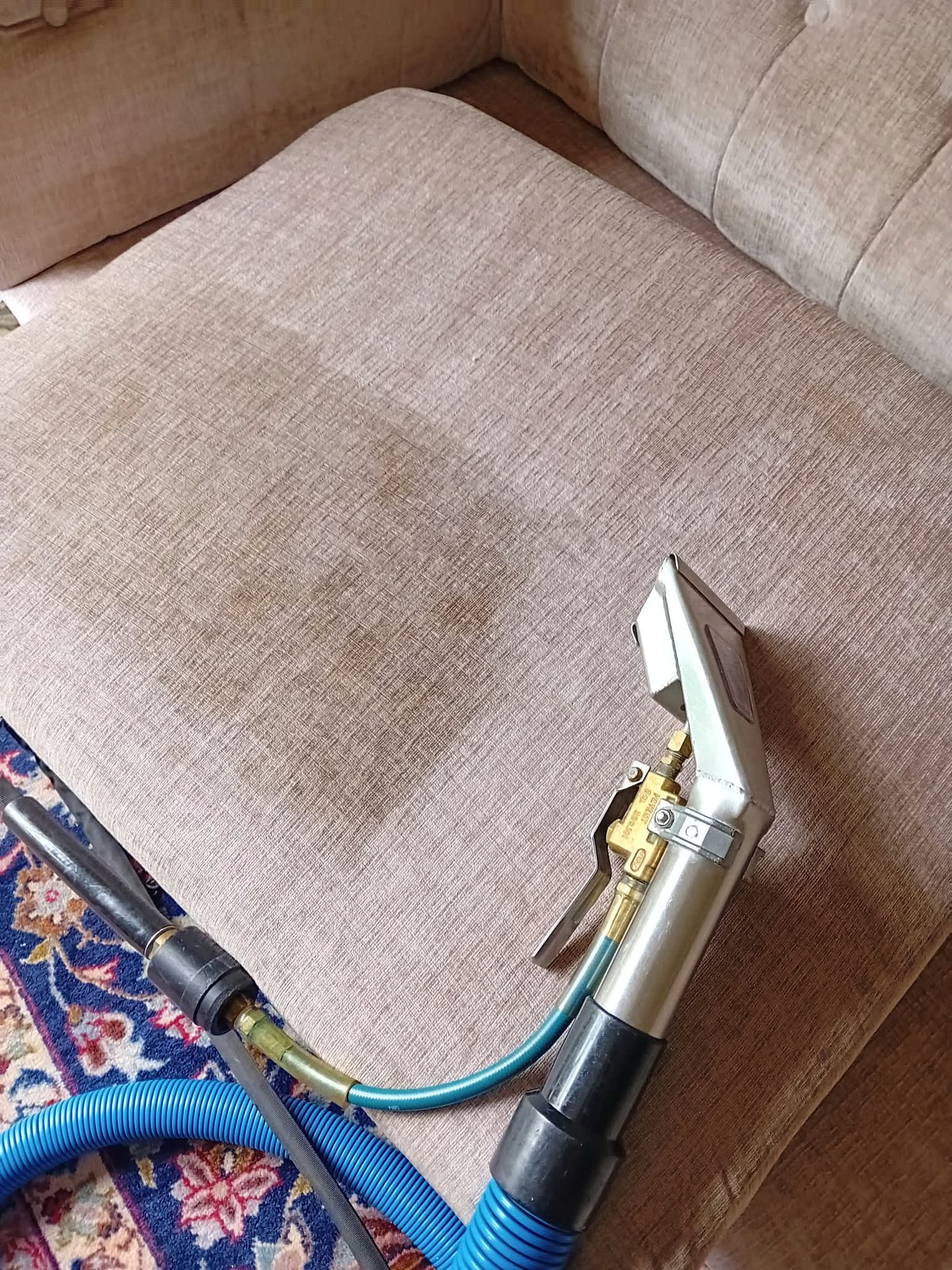 Fabric sofa cushion being deep cleaned with an upholstery extraction tool to lift a set-in stain