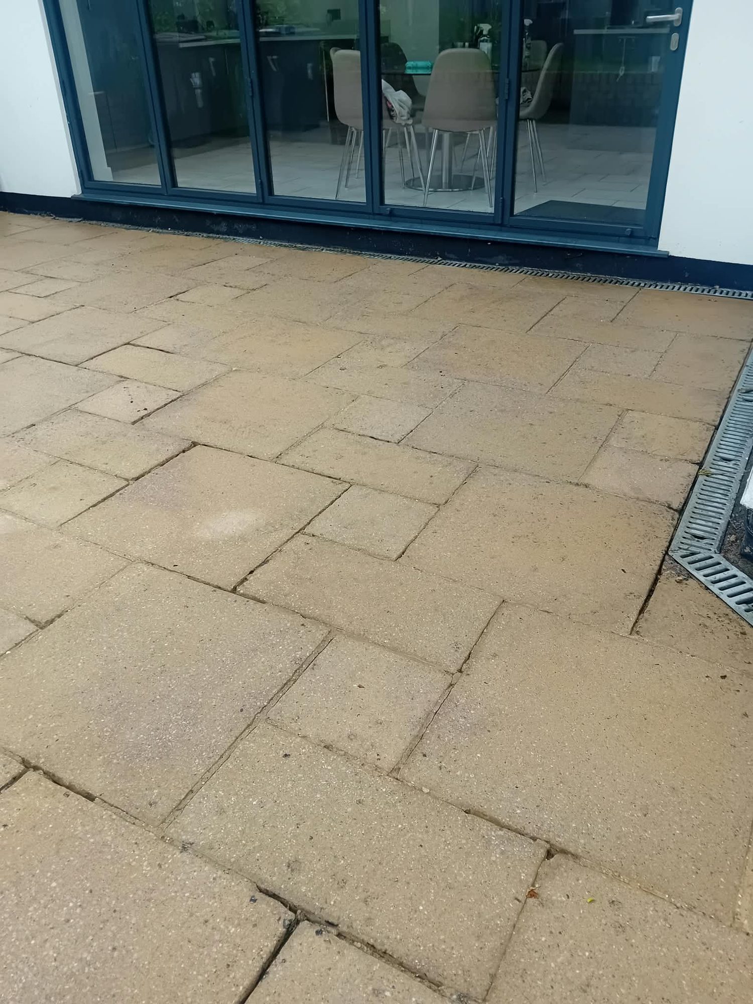 Large sandstone patio slabs cleaned in front of bi-fold doors on a modern North London home